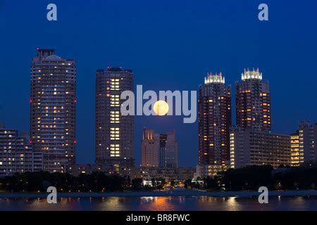 Night Scenery Of Full Moon Over Night City Skyline With Colorful Light