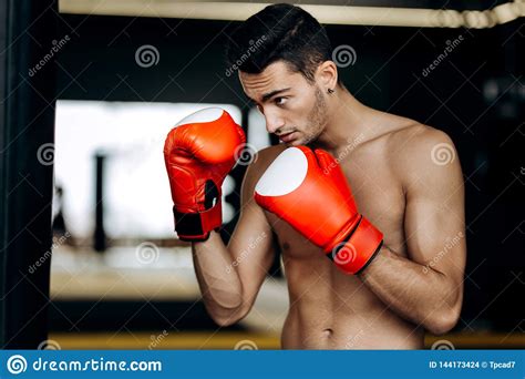 Sportsman With A Naked Torso And The Red Boxing Gloves On His Hands Stands On Guard In The