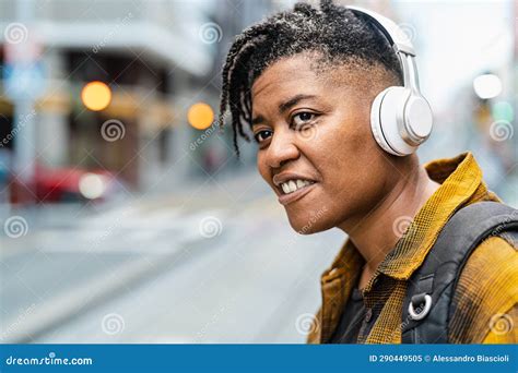 African Woman Listening To Music With Wireless Headphones While Waiting