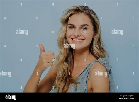 Cheerful Blonde Woman Showing Thumbs Up Gesture While Standing Slightly Sideways Expressing