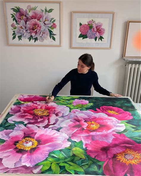 A Woman Is Painting Flowers On A Large Table Cloth In Front Of Two