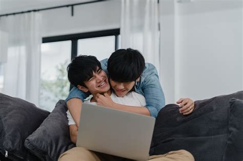 Jovem casal gay usando computador portátil em casa moderna os homens asiáticos lgbtq felizes