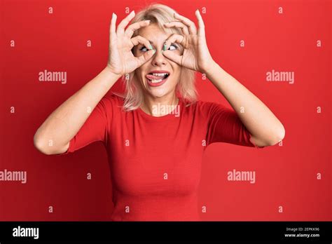 Jeune fille blonde portant des vêtements décontractés faisant un geste ok comme des jumelles qui