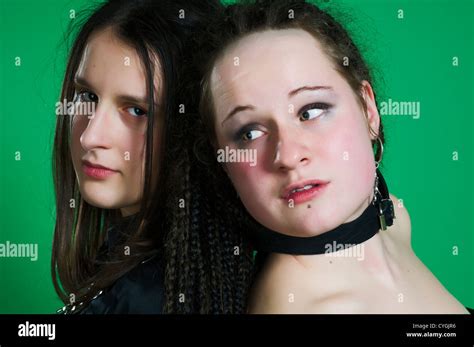 Two Lesbian Sexy Gothic Women With Dreads Wearing BDSM Outfit On Green Background Stock Photo