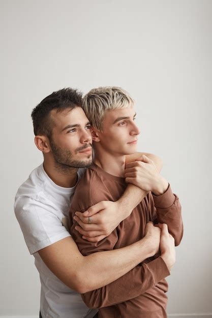Cintura vertical para cima retrato de um casal gay apaixonado se abraçando em casa e olhando