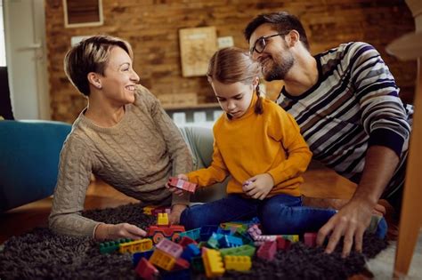 Familia feliz divirtiéndose mientras juega con bloques de juguete en