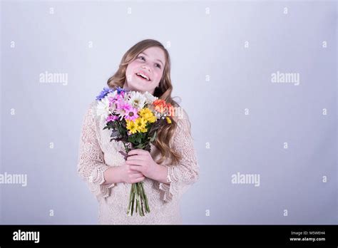 Twelve Year Old Girl With Long Dirty Blonde Hair Holding Colorful Bouquet Of Daisies Smiling