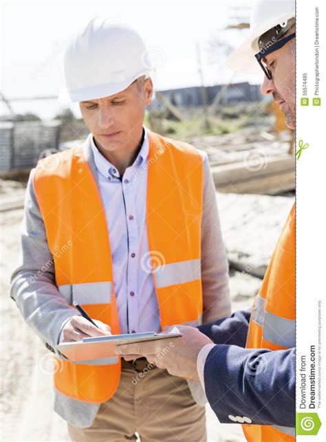 Ingenieros Que Escriben En El Tablero En El Emplazamiento De La Obra