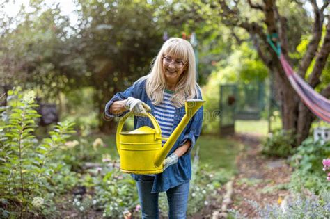 Mature Woman Watering Plants In Her Garden Stock Image Image Of Woman Older