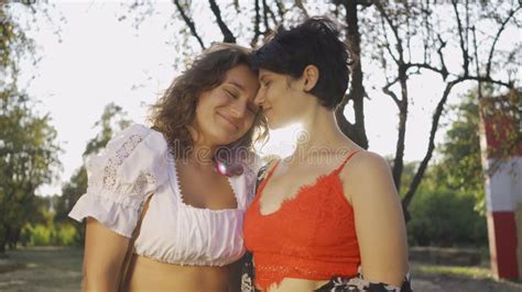Two Beautiful Lesbian Women Feel Shy Sitting On A Bench And Join Hands