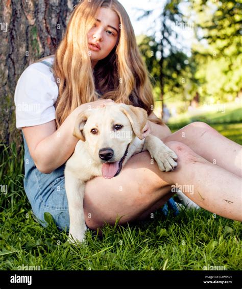 Junge attraktive blonde Frau spielen mit ihrem Hund im grünen Park im Sommer Lifestyle