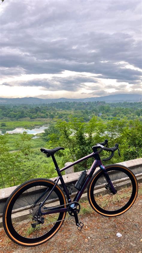 A Bike Parked On The Side Of A Road Next To A Lush Green Hillside Under