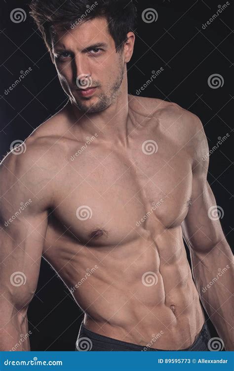 Homem Novo Muscular Descamisado Considerável No Fundo Escuro Imagem de