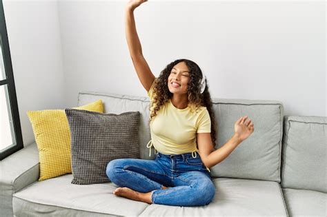 Joven latina sonriendo confiada escuchando música en casa Foto Gratis