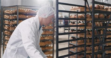 Good Looking Mature Man In White Uniform Load The Raw Bred On The Shelves To Be Transported To