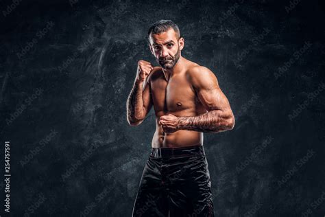 Professional Muay Thai Boxer With Naked Torso Posing For A Camera Studio Photo Against A Dark