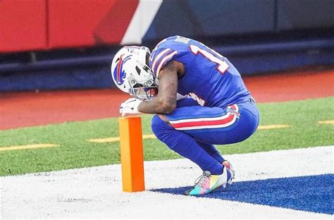 A Football Player Kneeling Down On The Sidelines With His Head In His