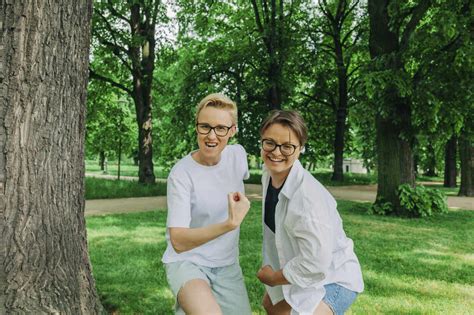 Playful Lesbian Couple Flexing Muscles At Park Stock Photo