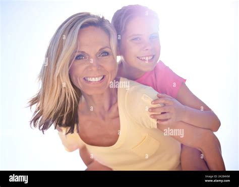 Vacation Fun With Mom A Smiling Mother With Her Daughter On Her Back