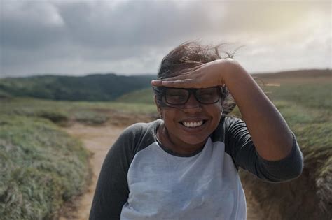 Mujer mulata latina en un prado cubriéndose del sol con la mano y sonriendo Foto Premium