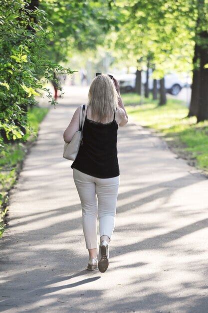 Premium Photo Blonde Walks Down A Spring Alley Back View