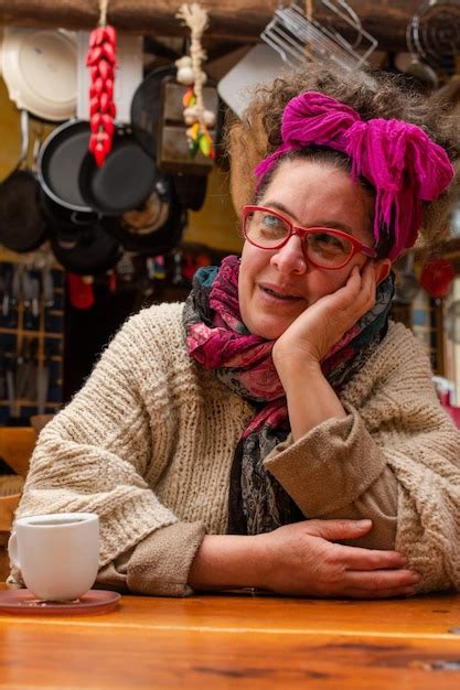 Mujer latina con velo y gafas sentada en una cocina prestando atención Foto Premium