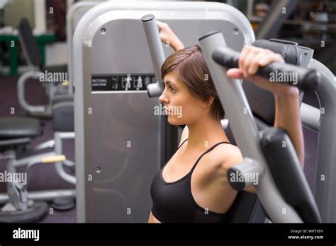 Athletic Brunette Using Weights Machine For Arms At The Gym Stock Photo Alamy