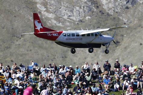 A Plane Flies Over The Crowd On The Grass Banks