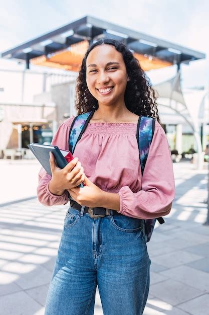 Confian A Estudante Universit Ria Latina Sorridente Em P E Segurando Livros Fora Do Shopping