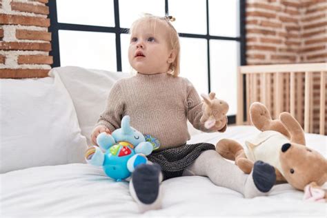 Adorable Blonde Girl Holding Doll Sitting On Bed At Bedroom Stock Image Image Of Comfort