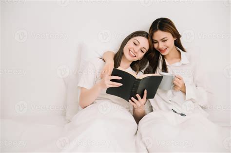 Attractive Lesbian Couple Use Mobile Phone Tablet Watch Movie On Bed Beautiful Sibling In