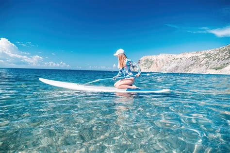 Mujer sana feliz en forma de bikini relajándose en una tabla de surf sup flotando en el mar