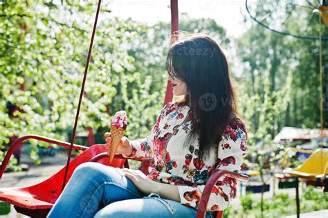 Portrait Of Brunette Girl In Pink Glasses And Hat With Ice Cream At Amusement Park