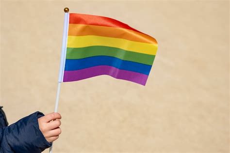 Segurando a bandeira do arco íris do símbolo do orgulho gay Foto Premium