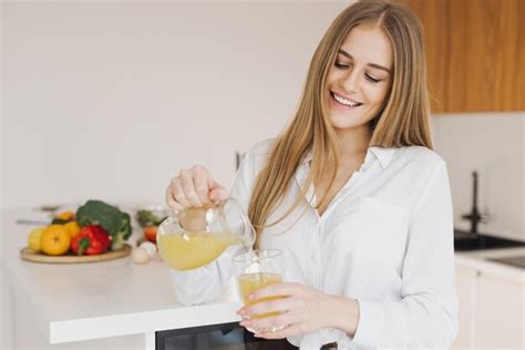 Premium Photo A Happy Cute Blonde Woman Drinks Orange Juice In The Kitchen