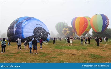 Row Of Partially Inflated Hot Air Balloons Rising Against Sunset Sky