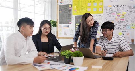 Asian woman and man team leader coach mentor talk to diverse employee in office explain strategy