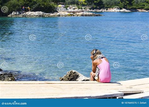 Ritratto Della Ragazza In Bikini Con Le Cuffie Che Si Siedono Sul Pilastro E Che Ascoltano La