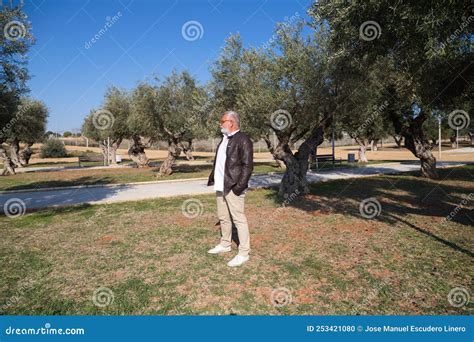Handsome Mature Man With Beard And Grey Hair Is Walking In The Park