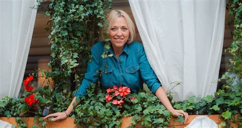Premium Photo Cute Blonde Girl On The Balcony With Flowers Enjoying The View And Fresh Air