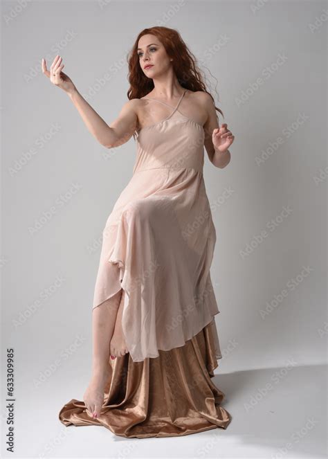 Full Length Portrait Of Beautiful Female Model With Long Brunette Hair Wearing A Creamy Pink