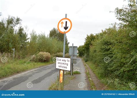give   oncoming vehicles sign   country lane stock photo