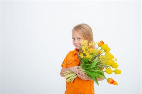 Jolie petite fille blonde vêtue d une robe tenant un bouquet de fleurs printanières sur fond