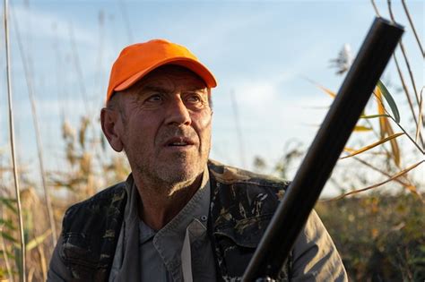 Premium Photo Mature Man Hunter With Gun While Walking On Field
