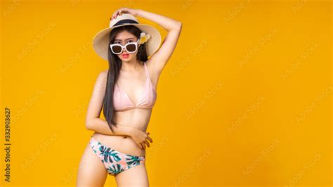 Beautiful Sexy Asian Girl Standing On Yellow Background In A Pink Bikini And Smiling Summer