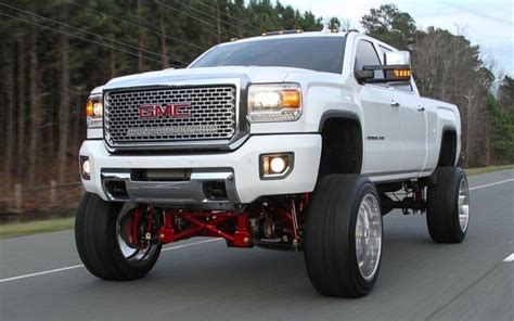 A White Truck Driving Down The Road With Big Tires On It S Front Wheels