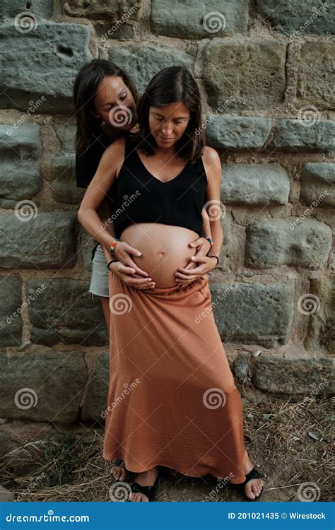 Vertical Closeup Of A Pregnant Lesbian Couple Doing A Photoshoot In A