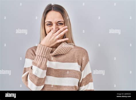 Jeune femme blonde portant un pull à col roulé sur un fond isolé qui sent quelque chose de