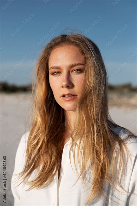 Blonde Woman With Long Hair Standing On The Beach Looking At Camera Stock Photo Adobe Stock