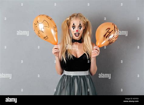 Excited Crazy Blonde Woman In Clown Make Up Holding Halloween Balloon Isolated Over Gray